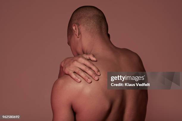 young man having shoulder pain - man touching shoulder stockfoto's en -beelden