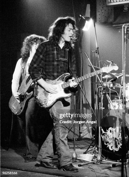 Rory Gallagher, with Gerry McAvoy behind, performs on stage at the Marquee Club in April 1972 in London. He plays a Fender Stratocaster guitar.