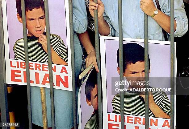 Posters of Elian Gonzalez are held by protesters at the Office of US Interests in Havana 10 December 1999 to request his return from the US. Varios...