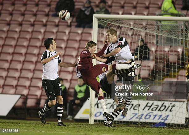 Stuart Giddings of Darlington heads the ball clear under pressure from Billy McKay of Northampton Town during the Coca Cola League Two Match between...