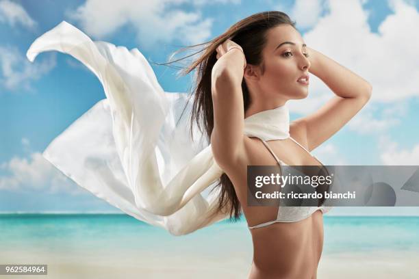 brunette girl wearing a bikini and a white scarf on a beach - sarong stock-fotos und bilder