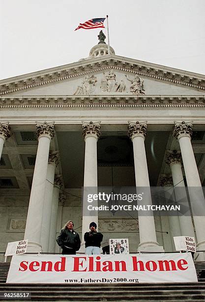 Two demonstrators stand beside a banner sponsored by the Father's Day 2000 organization in protest of keeping Cuban survivor Elian Gonzalez in the US...