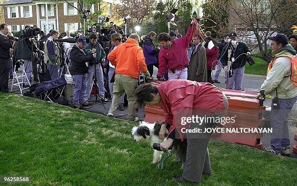 An unidentified woman walks her dog as members of the media set up their equipment in front of the home of Cuban diplomat Fernando Remirez in...