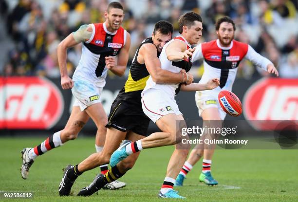 Jack Steele of the Saints kicks whilst being tackled by Toby Nankervis of the Tigers during the round 10 AFL match between the Richmond Tigers and...