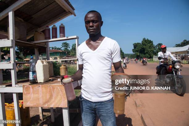 Olivier Muzombe, one of the street sellers of gasoline nicknamed "Kadafi", holds bottles of gasoline in a street seller in a southeastern district of...