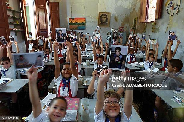 Young pupils at the school attended by six-year-old Elian Gonzalez hold pictures Elian, his father and half-brother 28 April 2000 in Cardenas, Cuba....