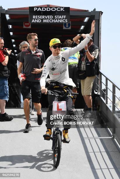 Renault's German driver Nico Hulkenberg waves as he leaves the paddock by bike ahead of the third practice session at the Monaco street circuit on...