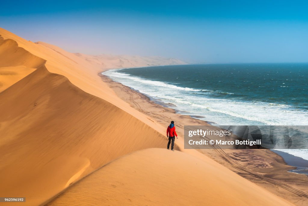 Tourist admiring the ocean from the top of a sand dune