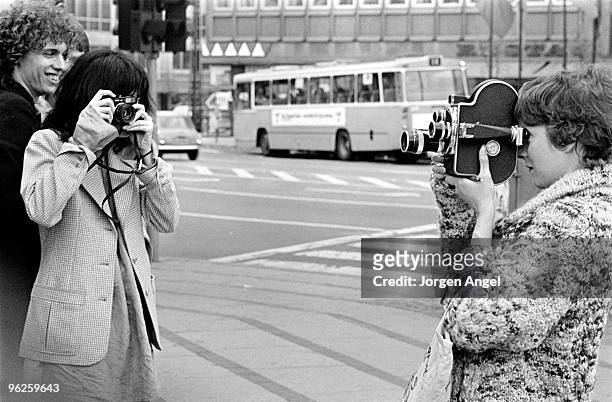 Patti Smith poses for a portrait with Richard Sohl taking pictures of a tourist with her Leica camera in May 1976 in Copenhagen, Denmark.
