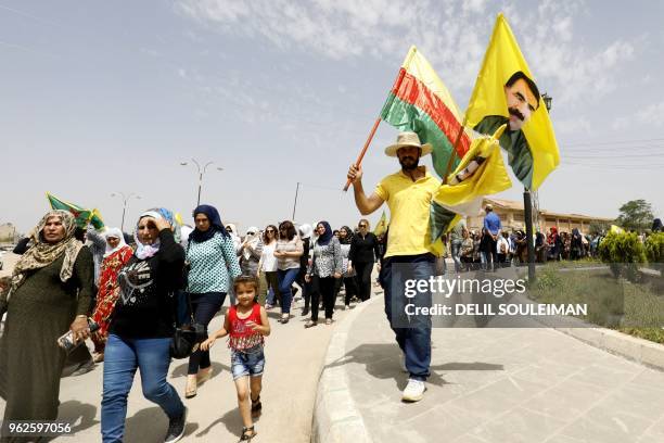 Syrian-Kurdish man holds a Kurdish flag as well as flags with the face of Kurdistan Worker's Party leader Abdullah Ocalan as people demonstrate...