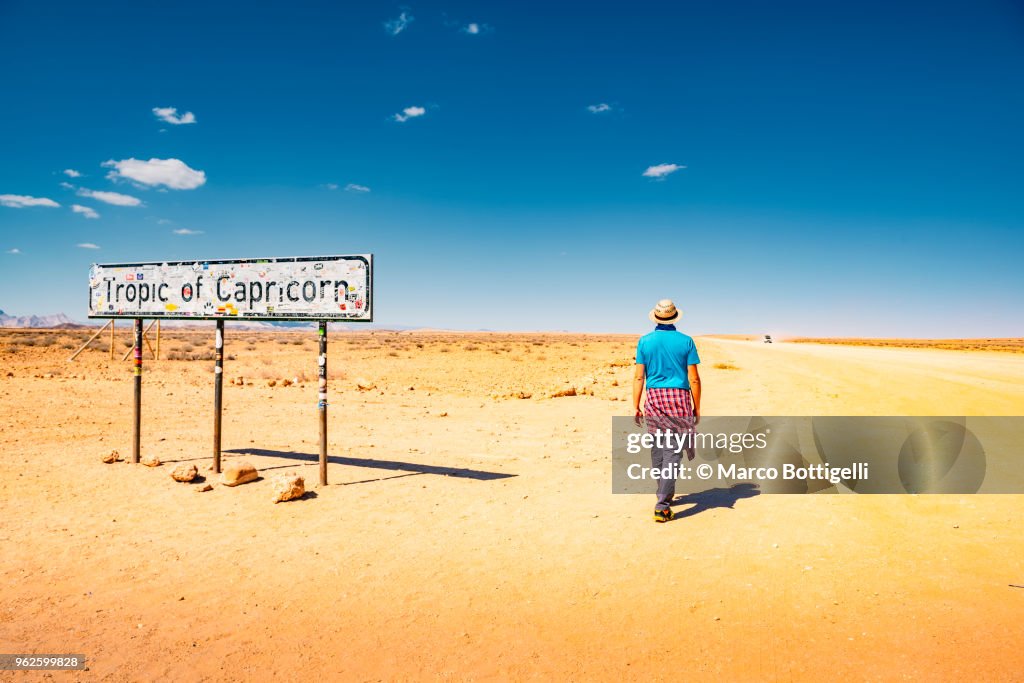 Tourist walking along a dirt road at the Tropic of Capricorn, Namibia