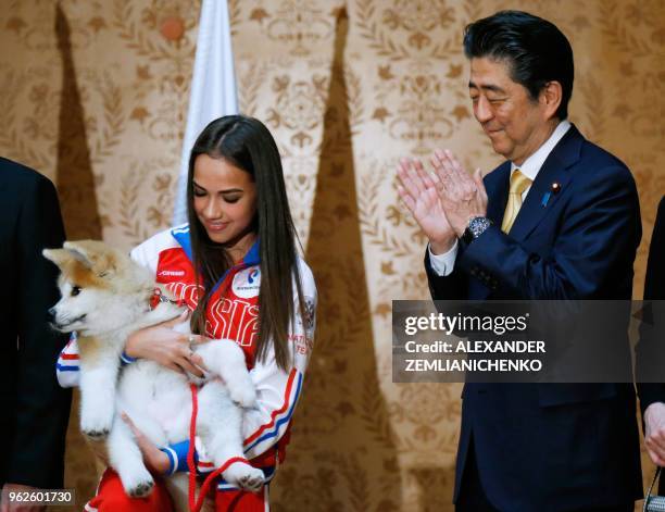 Russian figure skating gold medallist Alina Zagitova holds an Akita Inu puppy named Masaru presented by Japanese Prime Minister Shinzo Abe in Moscow...