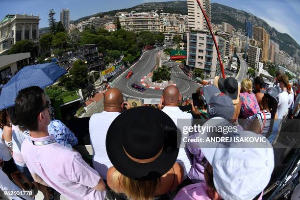 Spectators on a balcony watch as Toro Rosso's New Zealand driver Brendon Hartley drives ahead of Ferrari's German driver Sebastian Vettel during the...