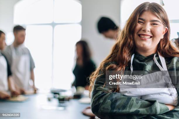 a young woman looking at the camera in a community center cooking class - indigenous canada stock pictures, royalty-free photos & images