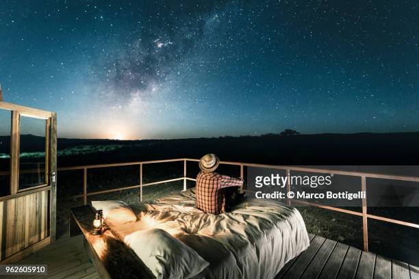 tourist sitting in bed outdoors under a starry sky - turismo ecológico fotografías e imágenes de stock