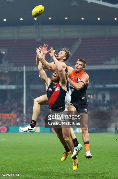 Adam Tomlinson of the Giants competes for the ball against Dyson Heppell and James Stewart of the Bombers during the round 10 AFL match between the...