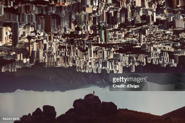 silhouette of man standing on top of mountain with urban cityscape turning up side down - free istock fotografías e imágenes de stock