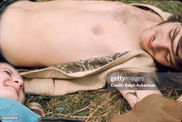 Close-up of a young oouple as they lie on the grass and smile at one another during the Woodstock Music and Arts Fair, Bethel, New York, August 1969....