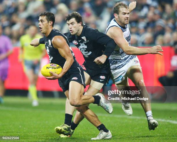 Ed Curnow of the Blues runs with the ball from Stewart Crameri of the Cats with help from Lachie Plowman of the Blues during the round 10 AFL match...