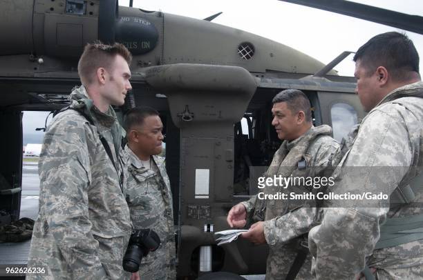 Photograph of soldiers involved in Task Force Hawaii consulting with one another prior to an aerial survey of areas affected by recent volcanic...
