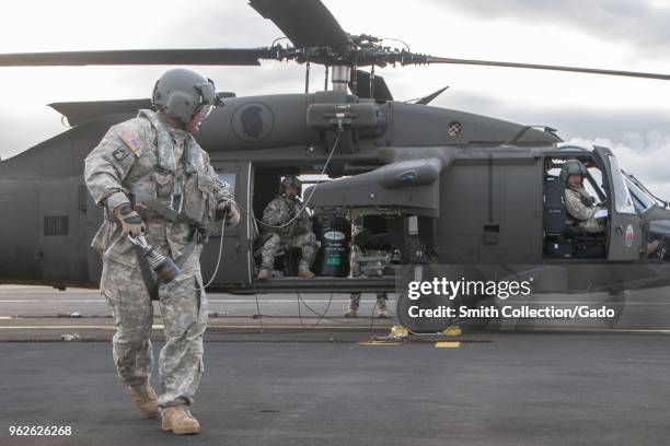 Photograph of Sergeant Christopher Pacheco testing a hoist cable outside of a grounded HH-60 Black Hawk helicopter, Lyman Airfield, Hilo, Hawaii, May...