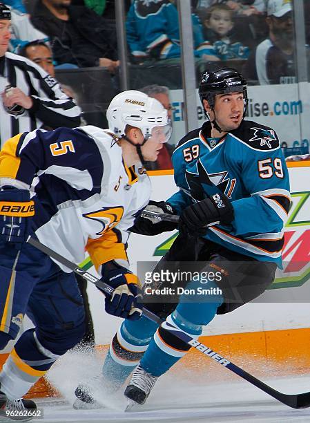 Toni Lydman of the Buffalo Sabres and Brad Staubitz of the San Jose Sharks change directions to chase down the puck during an NHL game on January 23,...