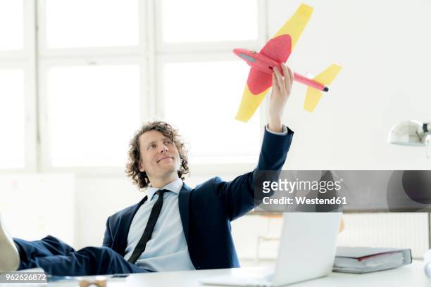 businessman sitting in his office playing with a toy plane - business jet stock-fotos und bilder