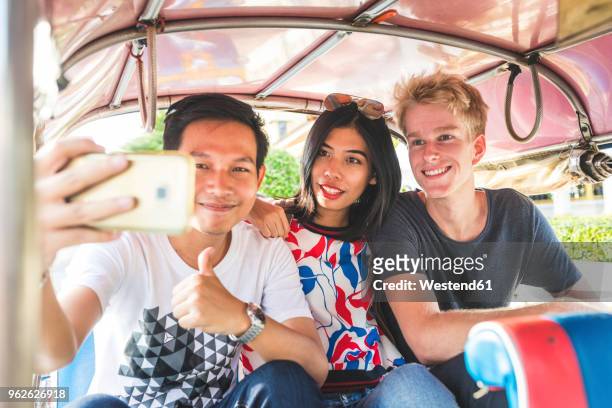 thailand, bangkok, three friends riding tuk tuk taking selfie with smartphone - motorriksha bildbanksfoton och bilder