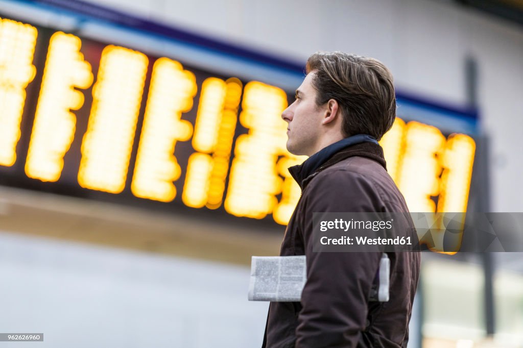 UK, London, businessman at train station looking at timetable