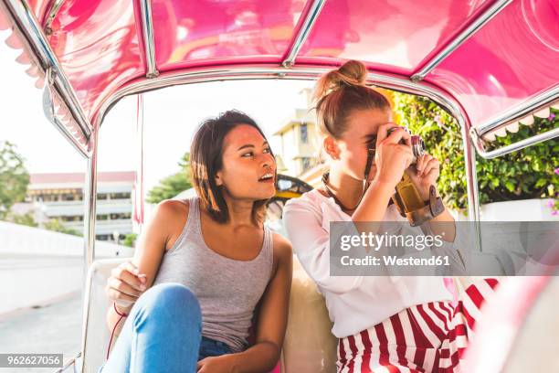 thailand, bangkok, two friends riding tuk tuk taking pictures with an old camera - 三輪タクシー ストックフォトと画像