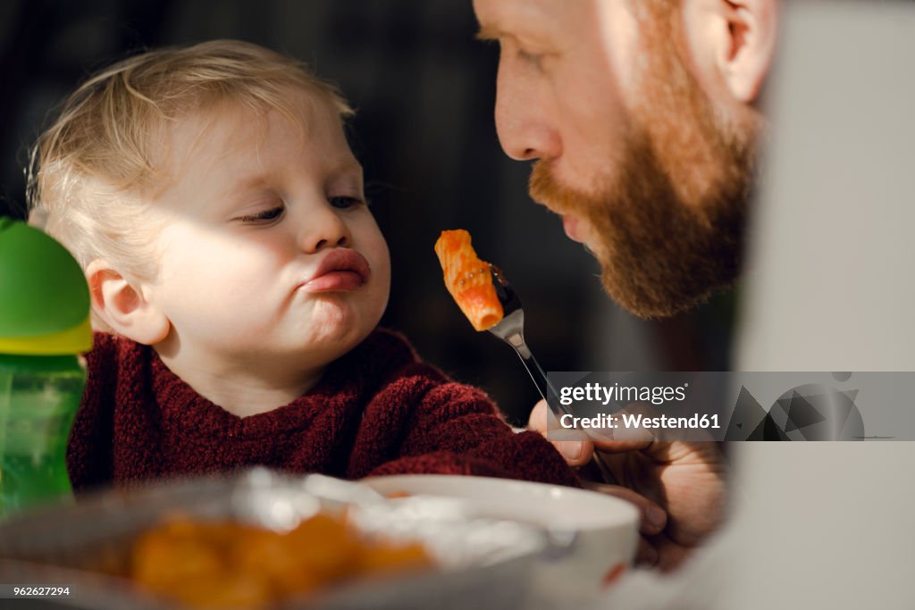 Father feeding his little son with tasty pasta
