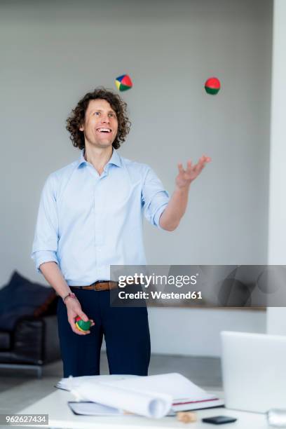 laughing businessman juggling balls in his office - juggling stock pictures, royalty-free photos & images