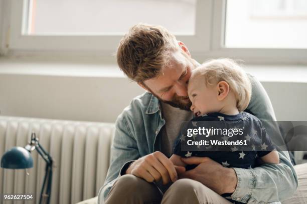 father spending time with his son at home - auf dem schoß stock-fotos und bilder