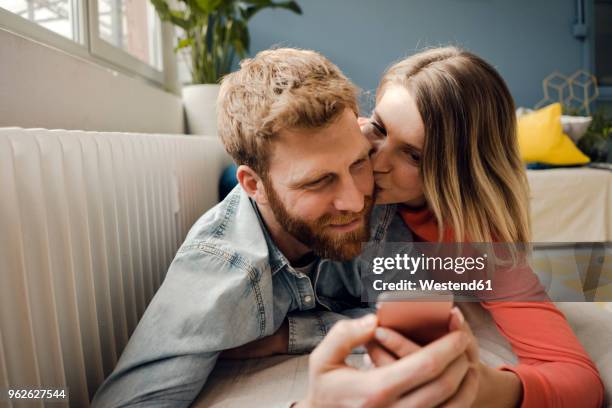 happy couple at home - happy couple using cellphone stockfoto's en -beelden