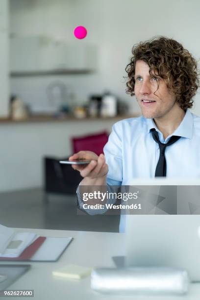 businessman playing ping pong with a ball and his mobile phone - german film ball 2018 stock-fotos und bilder