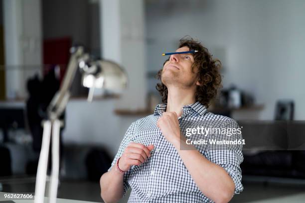 businessman balancing pencil on his face - boring man stock-fotos und bilder