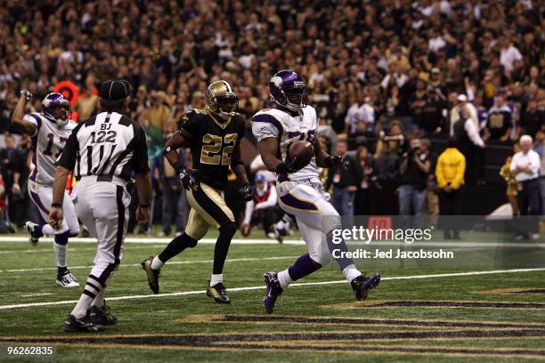 Adrian Peterson of the Minnesota Vikings scores a touchdown in the first quarter against Tracy Porter and the New Orleans Saints during the NFC...