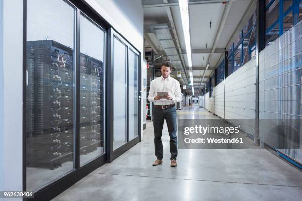 businessman using tablet in modern factory - centre de traitement de données photos et images de collection
