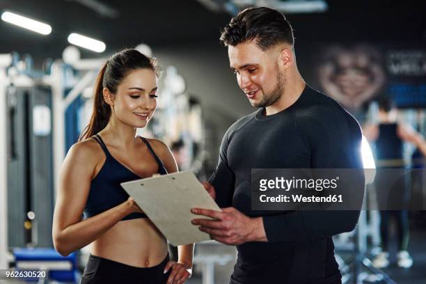 personal trainer talking to woman in gym - fitness instructor stock-fotos und bilder