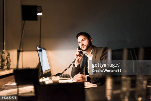 businessman on the phone in office at night - festnetzanschluss stock-fotos und bilder