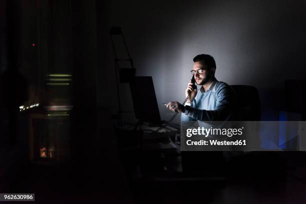 businessman on the phone in office at night - festnetztelefon stock-fotos und bilder