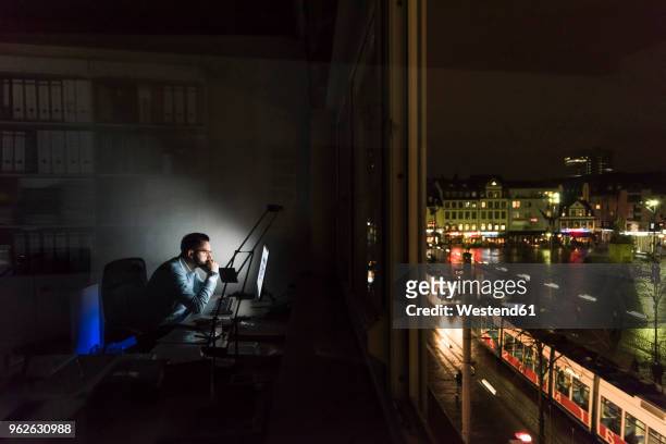 businessman working on computer in office at night - dunkel stock-fotos und bilder