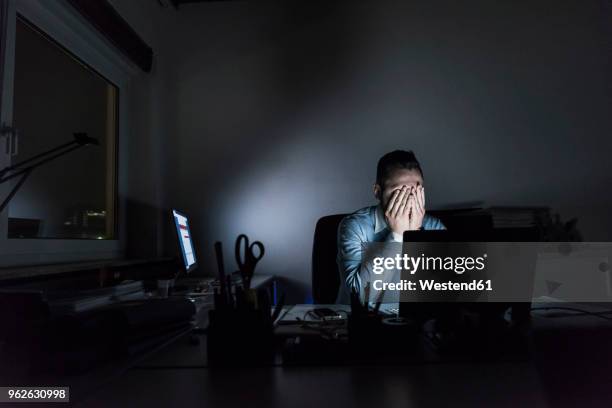 exhausted businessman sitting at desk in office at night - depressiv stock-fotos und bilder