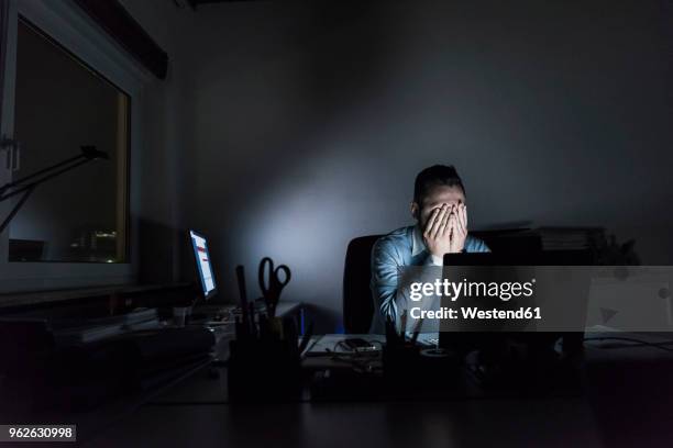 exhausted businessman sitting at desk in office at night - stress au travail photos et images de collection