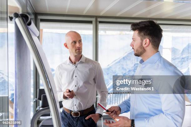 two businessmen having a discussion at flipchart in office - schweiz business stock-fotos und bilder