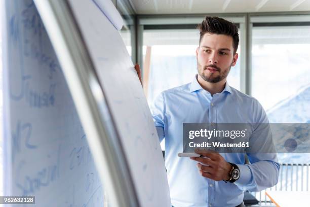 businessmen standing at flipchart in office - flipchart stock pictures, royalty-free photos & images