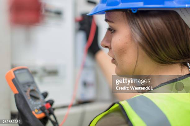 young female electrician working with voltmeter at fusebox - voltmeter stock pictures, royalty-free photos & images