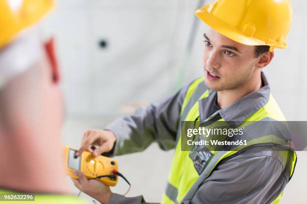 electricians working with voltmeter on construction site - voltmeter stock pictures, royalty-free photos & images