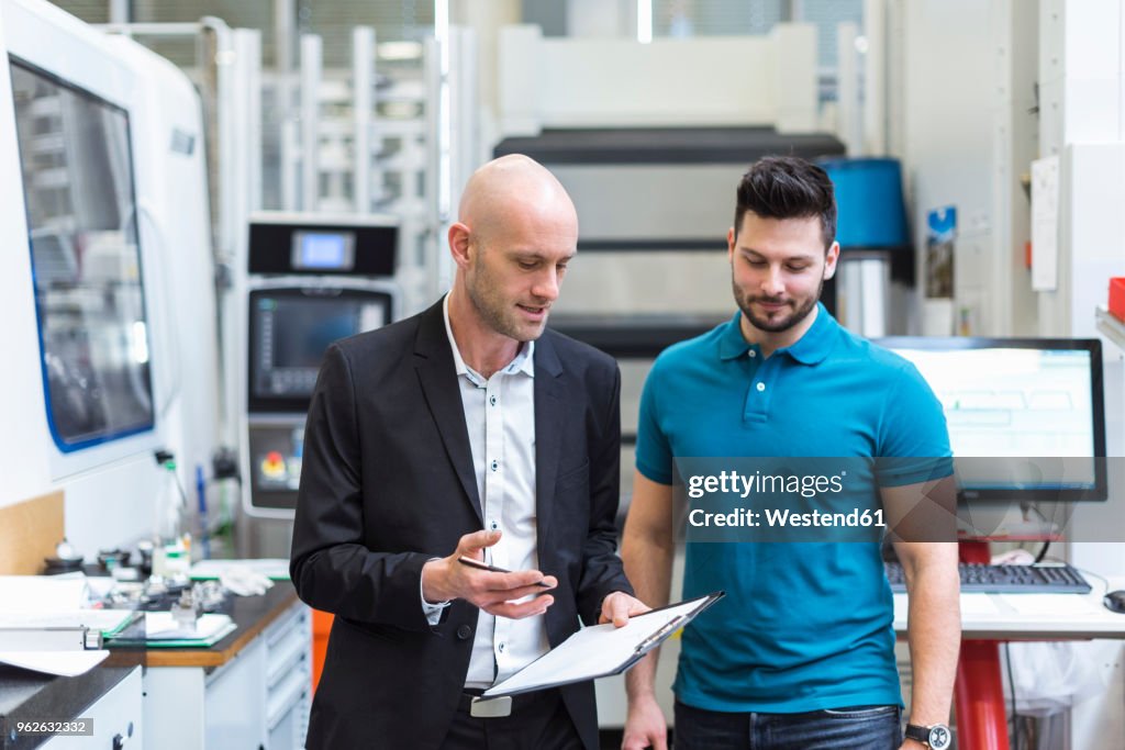 Businessman and employee discussing in modern factory