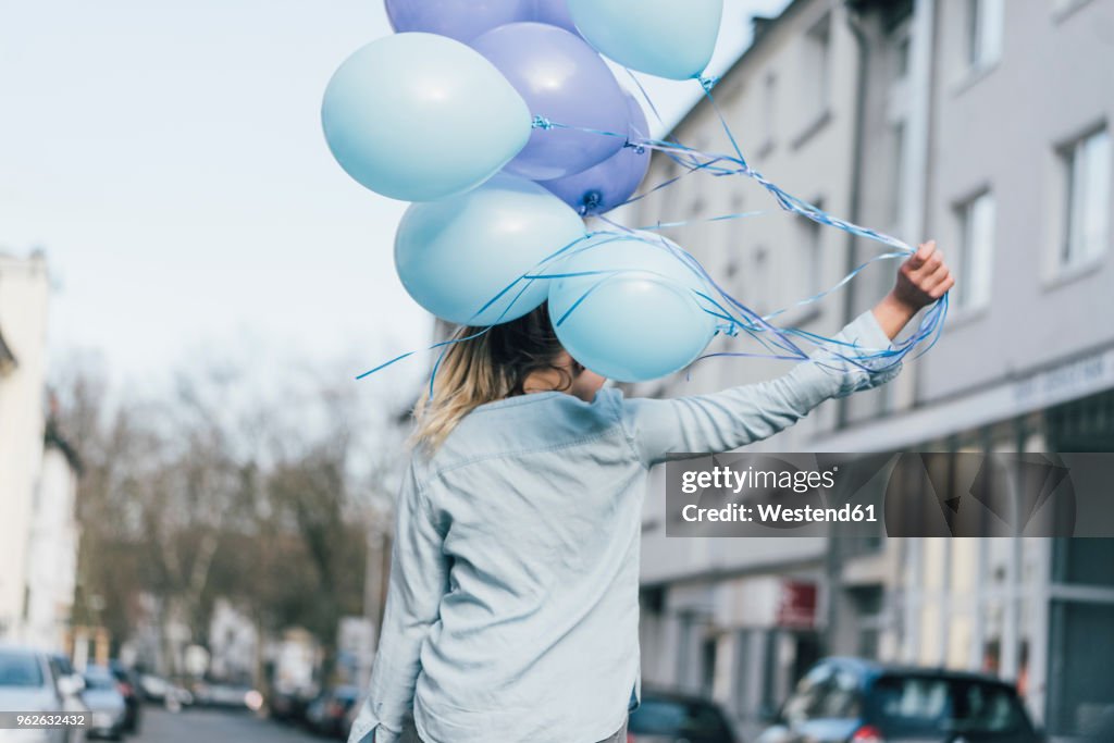 Back view of woman with blue balloons